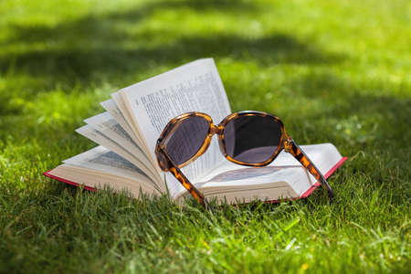 Book and sunglasses on a green grassの写真素材