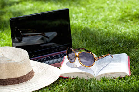 Hat, book, sunglasses and notebook on a grassの写真素材
