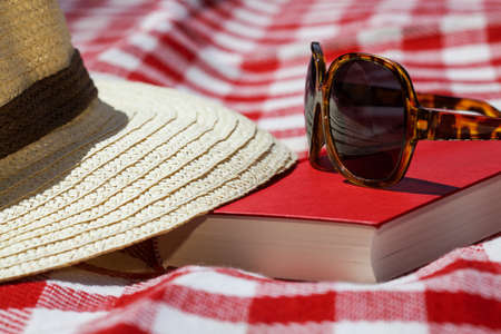 Closeup of a sunglasses, hat and bookの写真素材