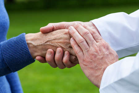 Doctor supporting an elderly woman, green background