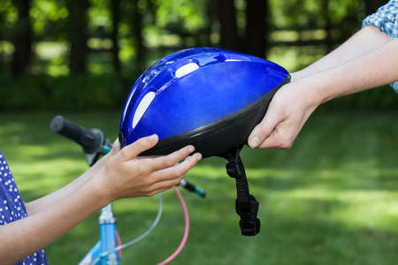 Close up of bicycle helmet held by two people