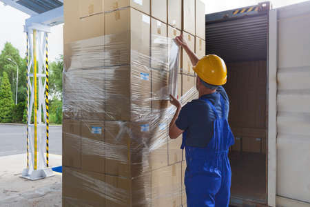 Foil putting on the boxes by a warehouse workerの写真素材