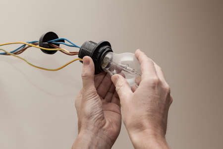 Closeup of mans hands screwing new bulb