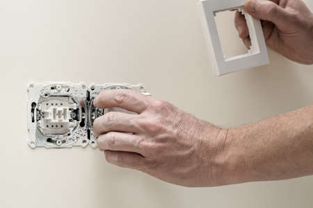 Man finishing a house, fitting light switch coverの写真素材