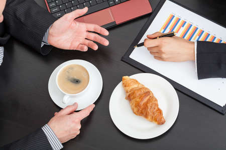 Business people with coffee and croissant at the meetingの写真素材