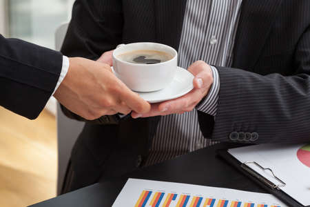 Woman giving a cup of coffee to businessman at the business meetingの写真素材