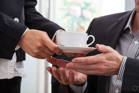 Woman hands giving a cup of coffee to a businessmanの写真素材