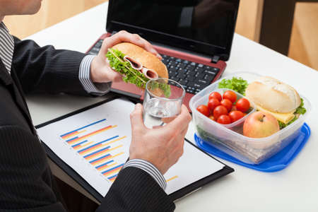 Hardworking manager eating a sandwich during work