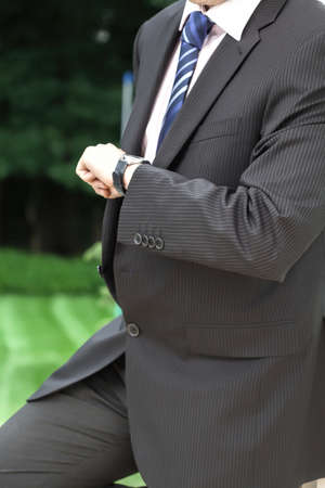 A businessman in a suit waitning and checking the timeの写真素材
