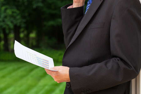 A businessman holding a sheet of paper with a graphの写真素材