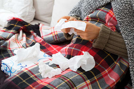 Sick woman blowing her nose with tissues