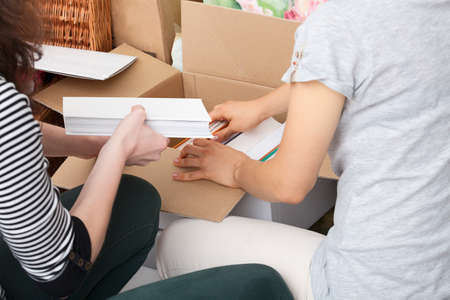 Women are packing books to the new flatの写真素材