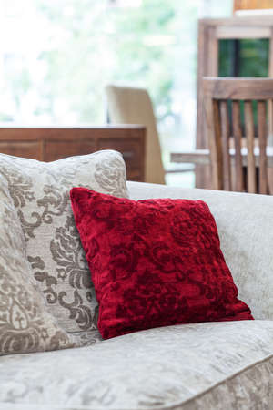 A closeup of an ecru sofa with a red velvet pillowの写真素材