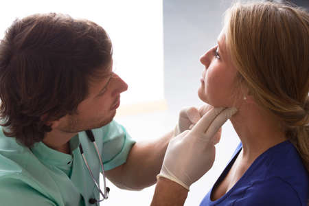 GP examining young woman, who has problems with throatの写真素材