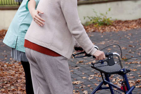 Nurse helping elder person to walk with walkerの写真素材