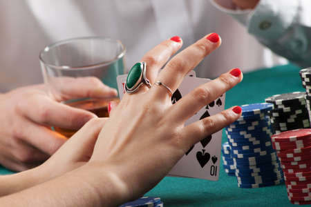 Woman hands on green casino table holding playing cards