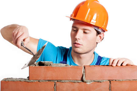 Construction mason installing red brick with trowel