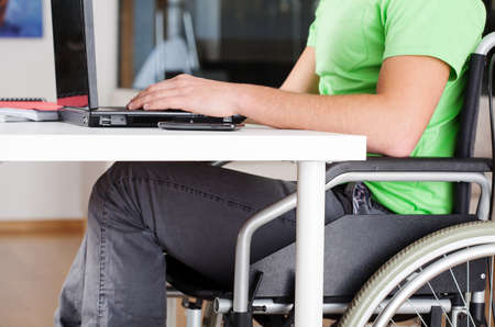Young man on wheelchair studying in his room