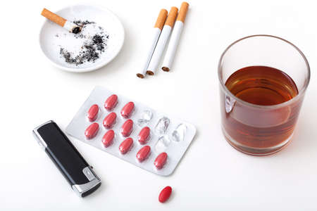 A glass of whisky, cigarettes, pills and a lighterの写真素材