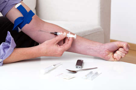 A close up of a drug addict shooting heroinの写真素材