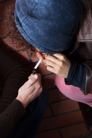 Young girl in blue blouse smoking a cigarette の写真素材