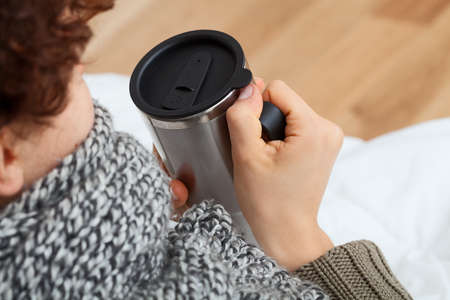 Sick woman with mug sitting on a couch 