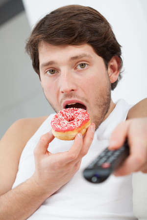 Man with donut and TV remote control