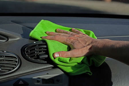 A man dusting a dashboard of a car with a ragの写真素材