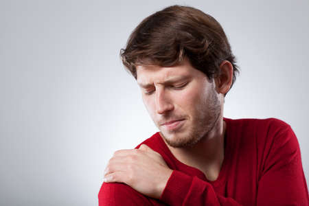 Young man is suffering from shoulder acheの写真素材
