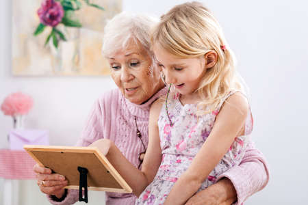 A grandmother looking at a family picture with her granddaughter