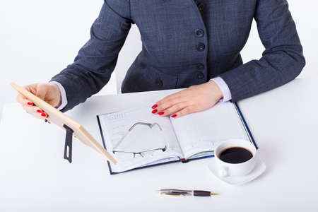 Modern businesswoman sitting in office with callendar looking at family photoの写真素材