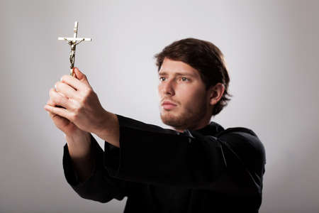 Priest holding a golden crucifix with respect