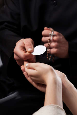 Catholic priest giving beliver a Holy Communion の写真素材