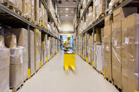 Warehouse worker with a yellow hand pallet truck