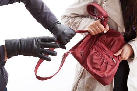 A closeup of a thief wearing gloves holding a woman's bagの写真素材