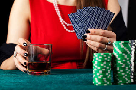 A female gambler with cards and a glass of whiskey