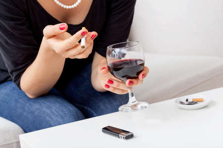 Woman smoking cigarette and drinking red wine