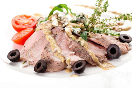 Sirloin in mustard sauce with tomatoes and black olivesの写真素材