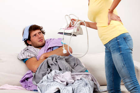 A woman making her husband iron his shirtsの写真素材