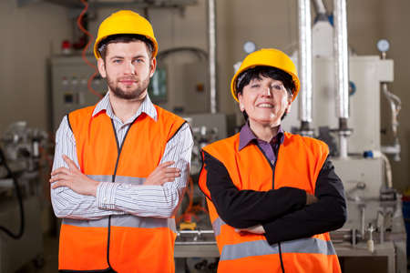 Happy team of employees at warehouse in yellow helmets and vestsの写真素材