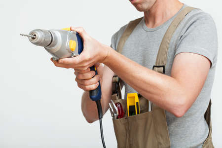 Handyman with silver drill on white isolated backgroundの写真素材