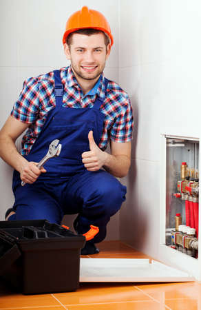 Young man repairing valves and pipes in bathroom