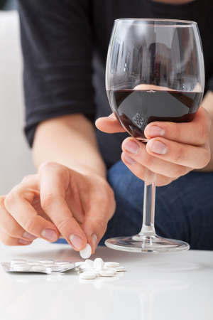 Woman taking a lot of pills with wineの写真素材