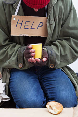 Homeless holding a cup of hot tea with a piece of bread