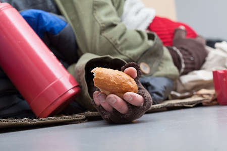 Poor man with piece of bread sleeping on a streetの写真素材