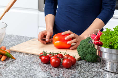 Young woman cutting vegetables to prepare dinner for family の写真素材