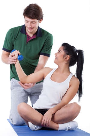 A woman working on her biceps using a dumbbell with a personal trainer
