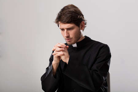 Young christian priest is saying a prayerの写真素材