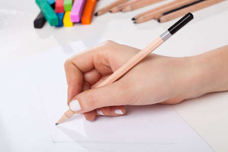 A closeup of a hand drawing a sketch with a pencil
