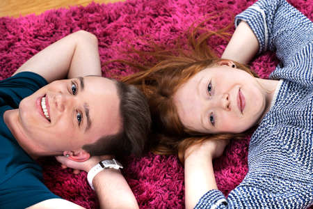Two happy teenagers friends lying together on carpet